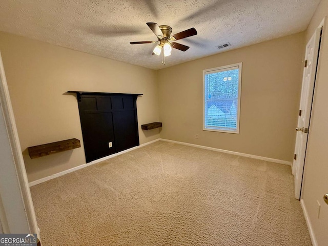 unfurnished bedroom with a textured ceiling, carpet floors, and ceiling fan