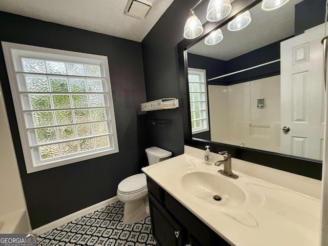 bathroom with vanity, a wealth of natural light, a textured ceiling, and toilet