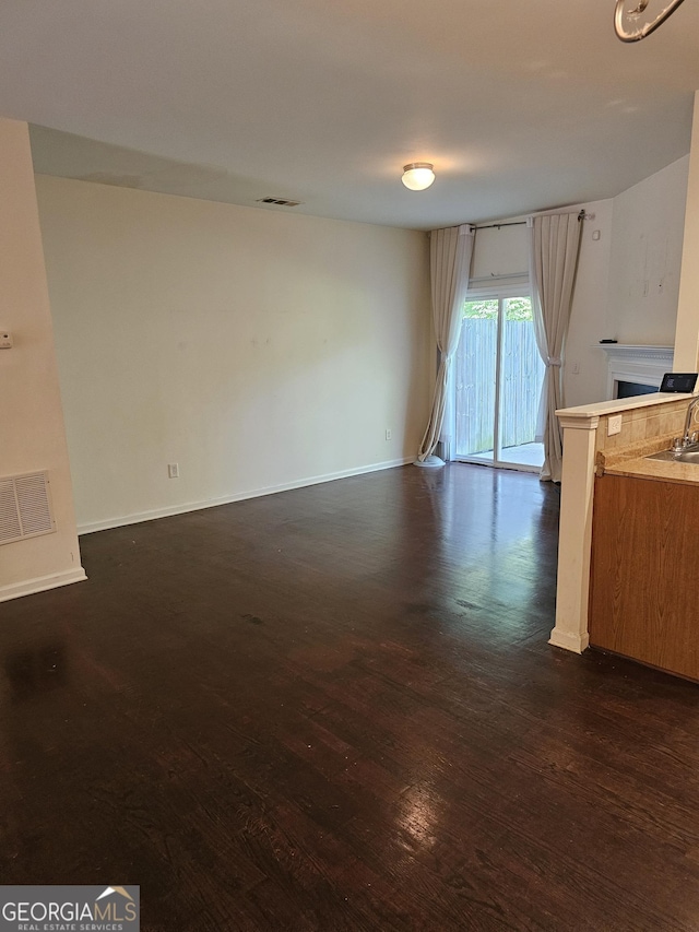 2764 Keystone Ave, Lithonia, GA 30058 - unfurnished living room with dark wood-style floors, a fireplace, baseboards, and a sink