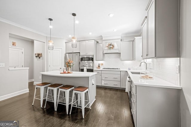 kitchen with a breakfast bar, sink, a center island, hanging light fixtures, and stainless steel appliances