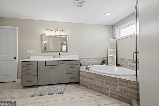 bathroom with vanity and tiled bath