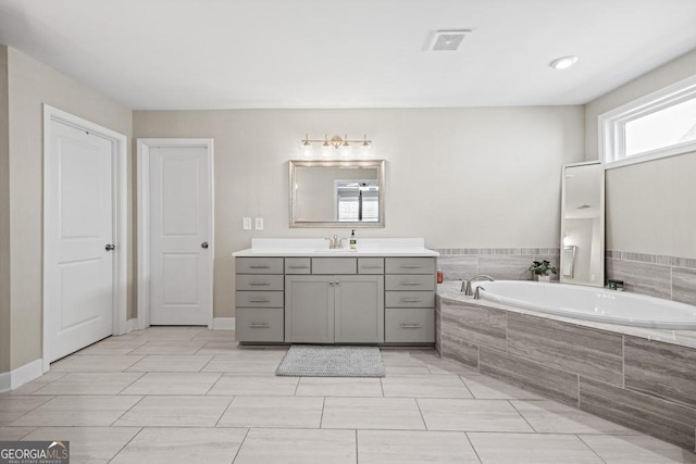 bathroom with vanity and tiled tub