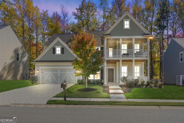 view of front of house with a balcony, a garage, covered porch, and a lawn