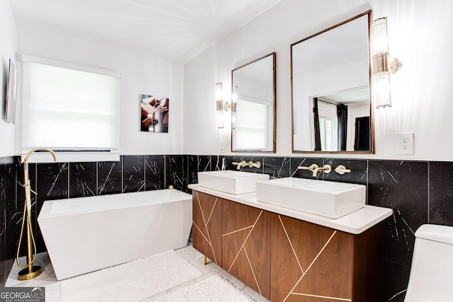 bathroom with vanity, a bathing tub, tile walls, and toilet