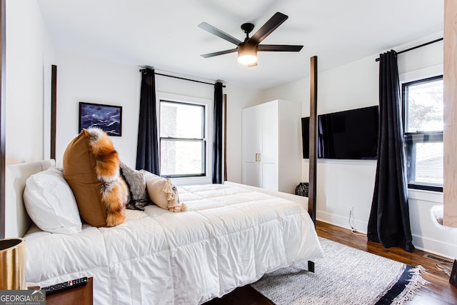 bedroom with multiple windows, dark wood-type flooring, and ceiling fan