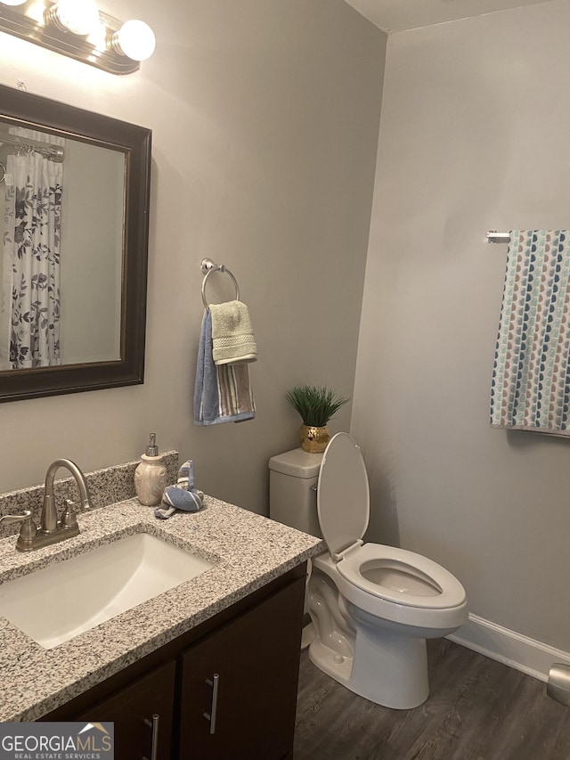 bathroom featuring wood finished floors, a shower with curtain, toilet, vanity, and baseboards