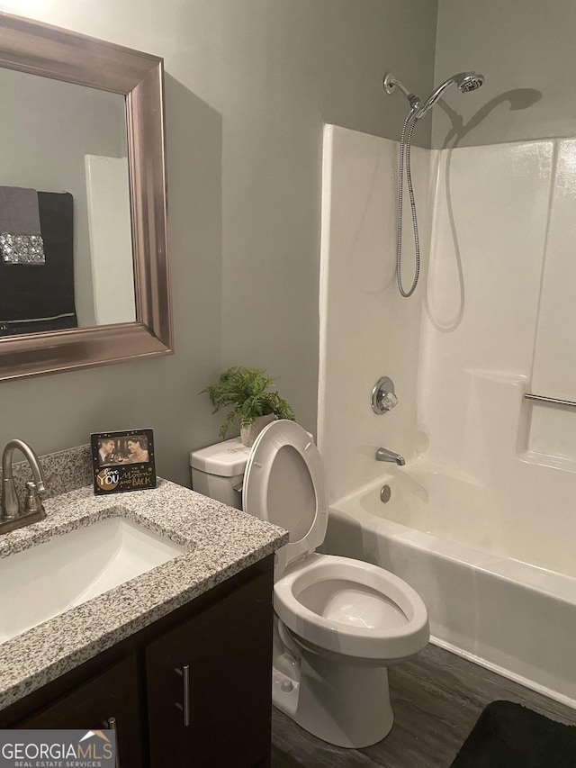 bathroom featuring toilet, wood finished floors, vanity, and shower / bathing tub combination