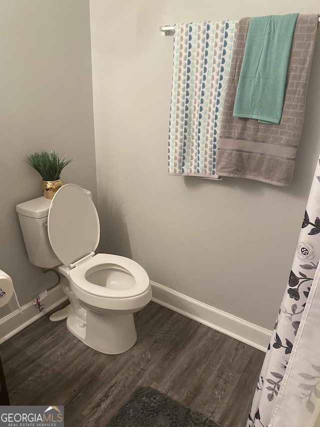 bathroom with wood finished floors, toilet, and baseboards