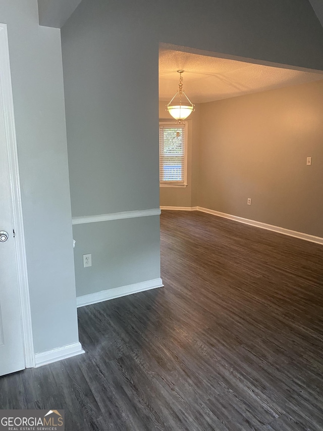 spare room with dark wood finished floors and baseboards