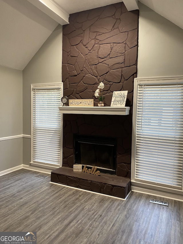 interior details featuring beam ceiling, wood finished floors, a stone fireplace, and baseboards