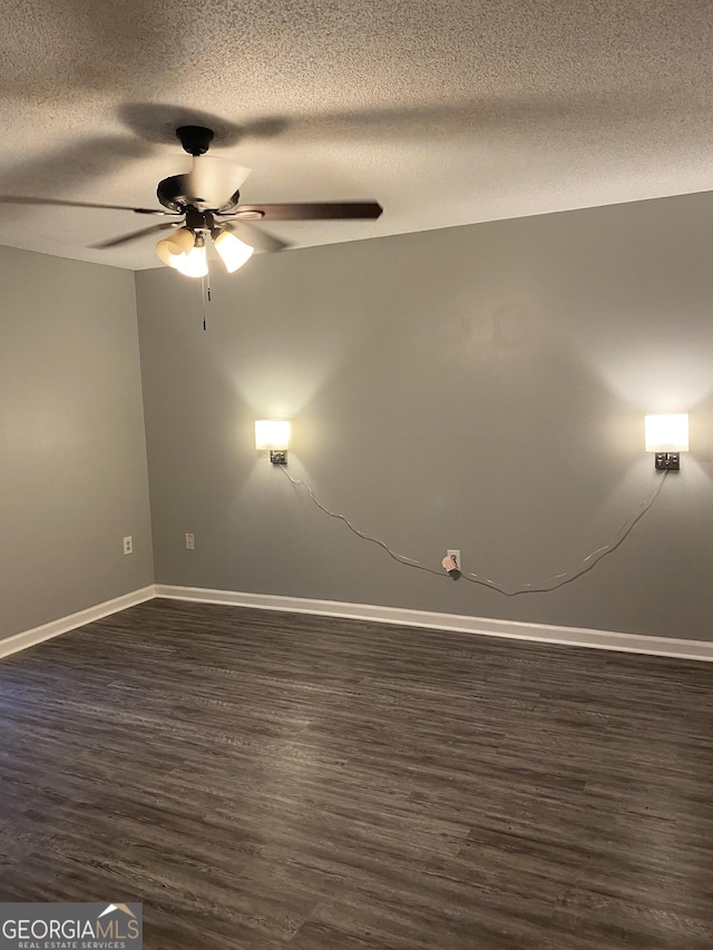 empty room with a textured ceiling, a ceiling fan, baseboards, and dark wood finished floors