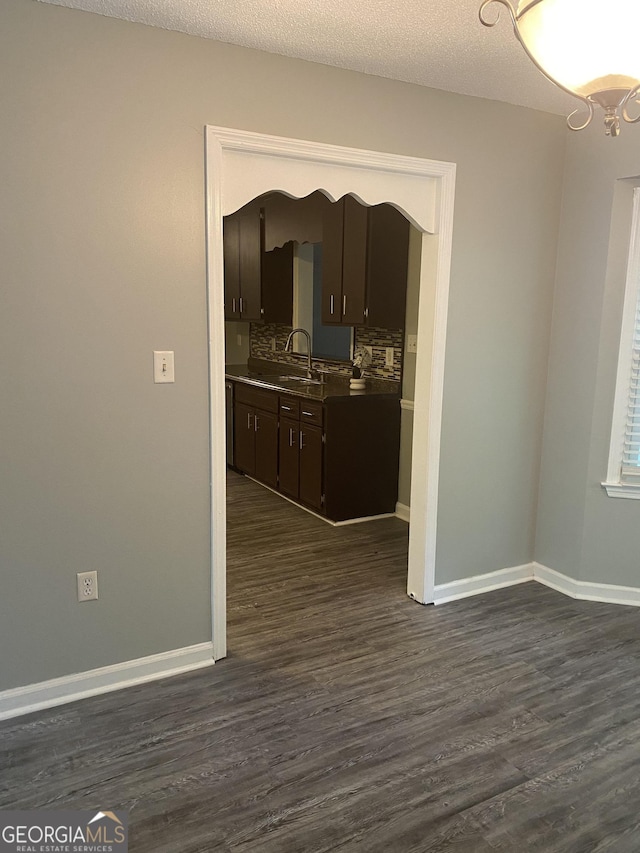 interior space featuring dark wood-style floors, a sink, and baseboards