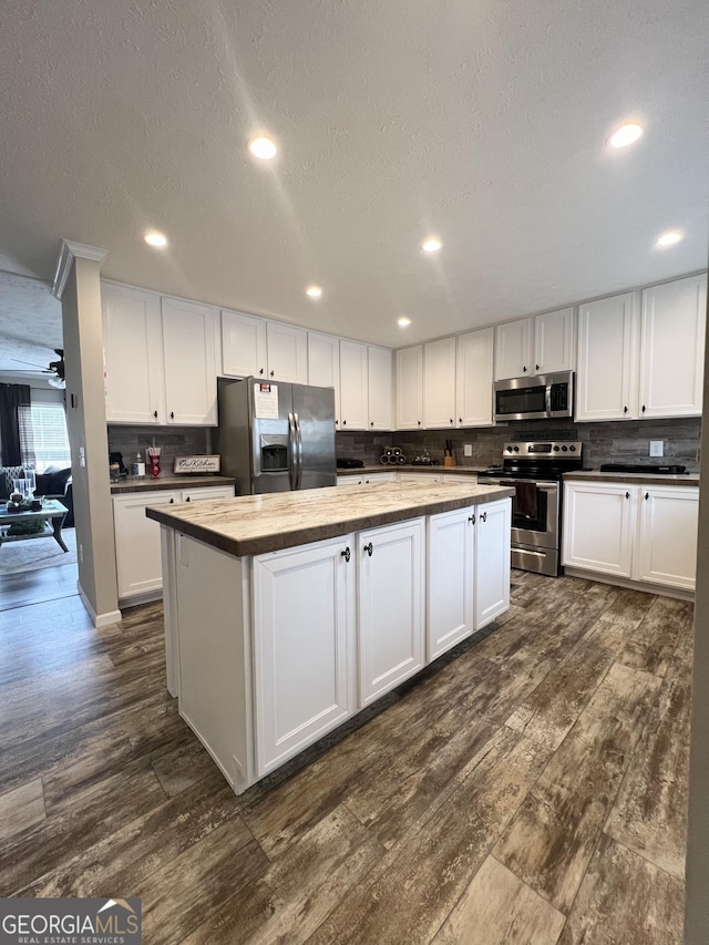 kitchen featuring dark wood-type flooring, wooden counters, appliances with stainless steel finishes, white cabinetry, and a kitchen island