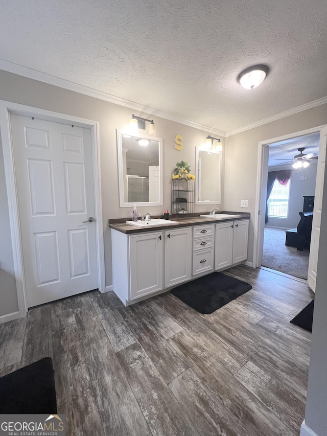 bathroom with wood-type flooring, a textured ceiling, vanity, and crown molding