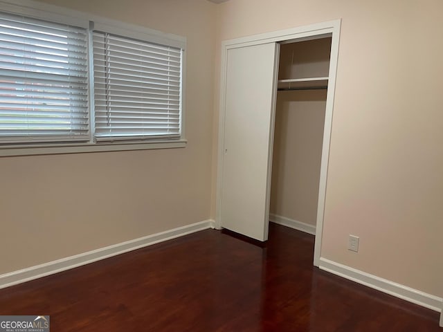 unfurnished bedroom featuring dark wood-type flooring and a closet