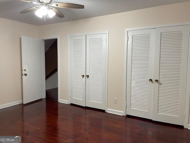 unfurnished bedroom featuring multiple closets, dark hardwood / wood-style floors, and ceiling fan