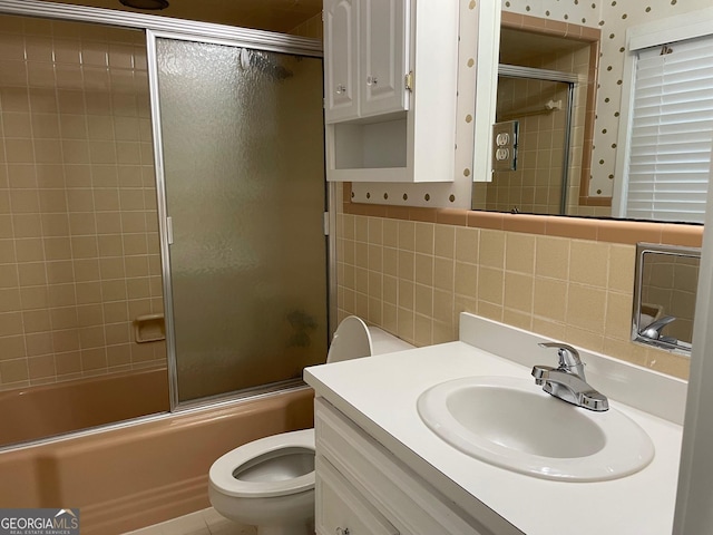 full bathroom with toilet, tasteful backsplash, tile walls, vanity, and enclosed tub / shower combo