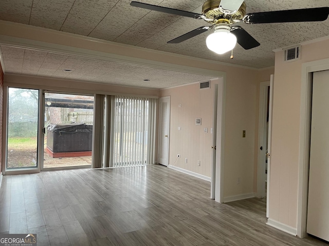 empty room with ornamental molding, hardwood / wood-style floors, and ceiling fan