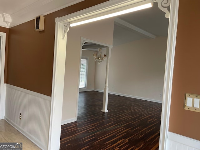 spare room with an inviting chandelier, ornamental molding, wood-type flooring, and vaulted ceiling with beams