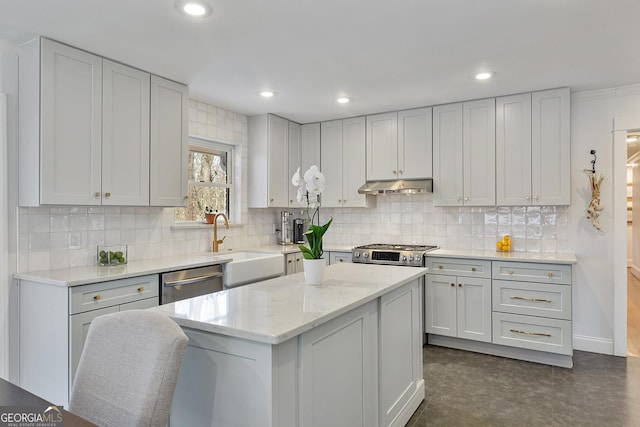 kitchen featuring stainless steel appliances, a kitchen island, light stone countertops, sink, and decorative backsplash