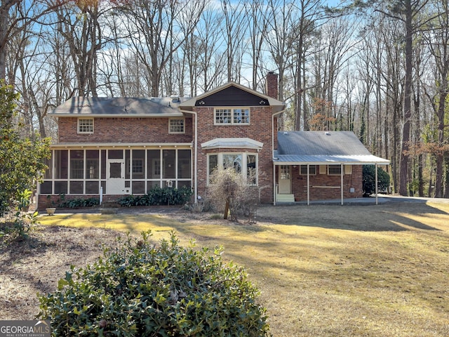 rear view of property with a sunroom and a lawn