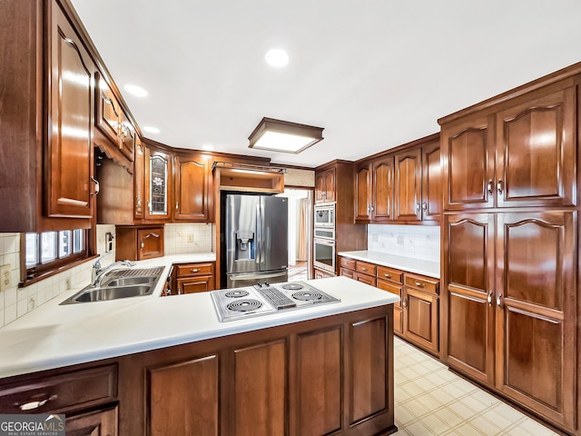 kitchen with stainless steel appliances, kitchen peninsula, sink, and backsplash