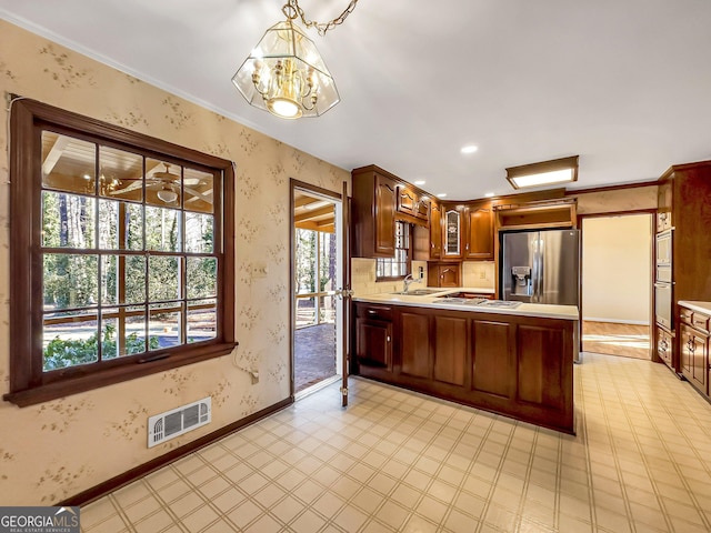 kitchen with sink, hanging light fixtures, gas cooktop, stainless steel fridge, and kitchen peninsula