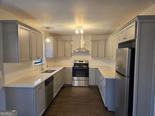 kitchen featuring pendant lighting, wall chimney range hood, sink, gray cabinetry, and stainless steel appliances