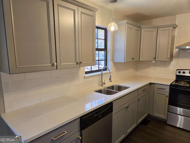 kitchen featuring light stone counters, appliances with stainless steel finishes, decorative light fixtures, and sink