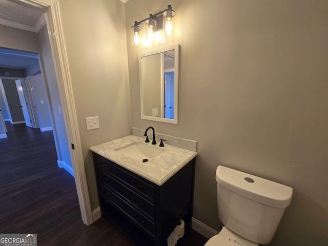 bathroom with vanity, hardwood / wood-style floors, crown molding, and toilet