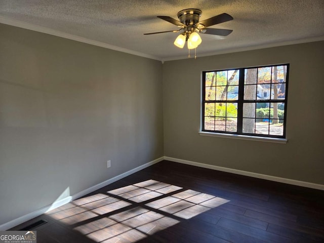 empty room with dark hardwood / wood-style flooring, a textured ceiling, ornamental molding, and ceiling fan