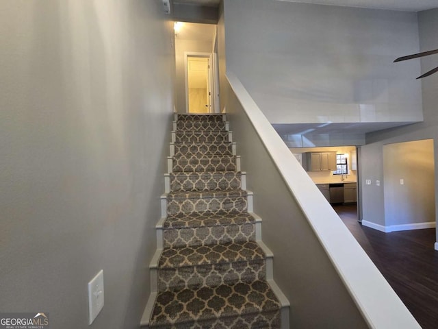 staircase with hardwood / wood-style flooring and ceiling fan