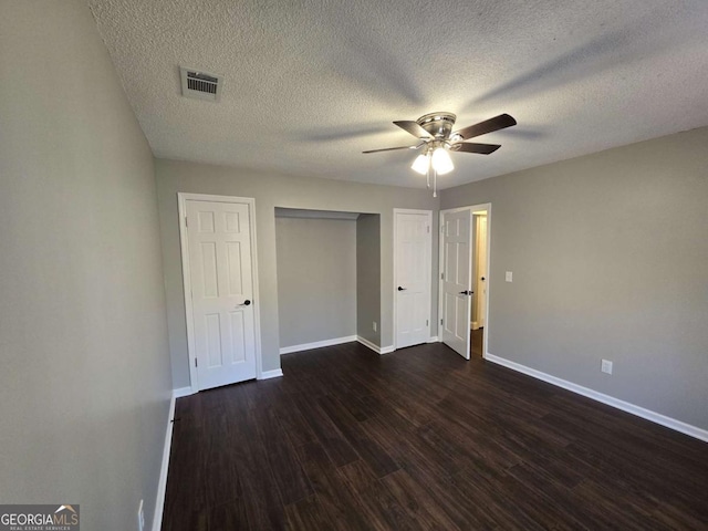 unfurnished bedroom with dark wood-type flooring, ceiling fan, a closet, and a textured ceiling