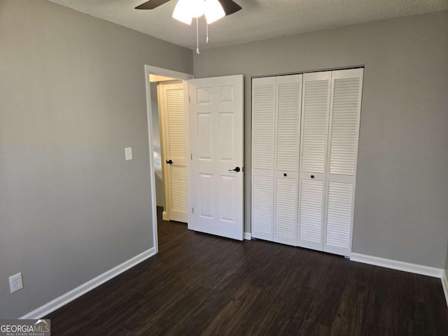 unfurnished bedroom with dark wood-type flooring, a textured ceiling, ceiling fan, and a closet