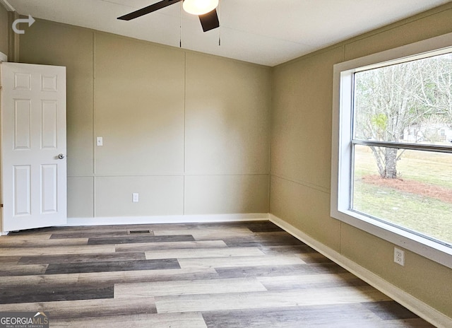 spare room featuring ceiling fan, a wealth of natural light, and wood-type flooring