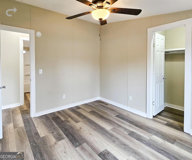 unfurnished bedroom with ceiling fan, hardwood / wood-style floors, a closet, and a walk in closet