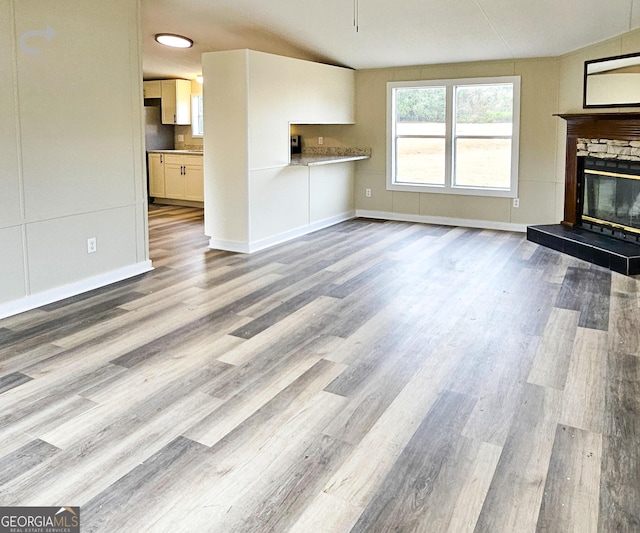 unfurnished living room with lofted ceiling, a fireplace, and light hardwood / wood-style flooring