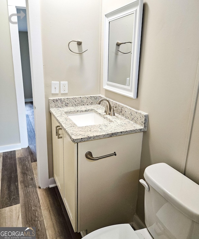 bathroom with vanity, wood-type flooring, and toilet