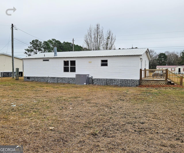 rear view of property featuring a wooden deck, a yard, and central AC