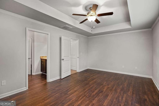 unfurnished bedroom featuring dark wood-type flooring, ceiling fan, a tray ceiling, and crown molding