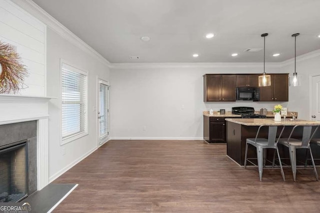 kitchen with a breakfast bar, pendant lighting, an island with sink, range, and dark brown cabinetry