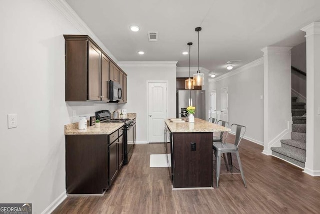 kitchen with sink, a kitchen breakfast bar, black appliances, an island with sink, and decorative light fixtures