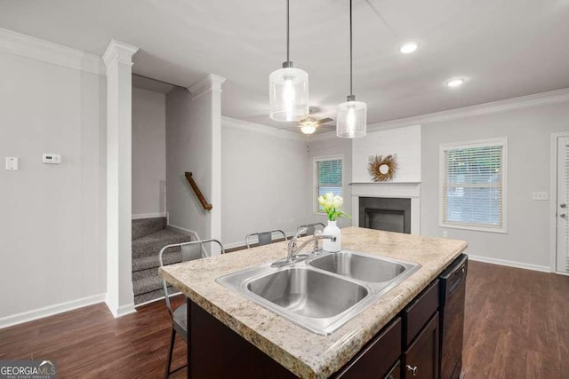 kitchen with pendant lighting, sink, black dishwasher, ornamental molding, and an island with sink