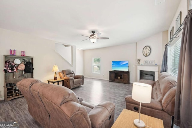 living room with dark wood-type flooring, ceiling fan, and a healthy amount of sunlight