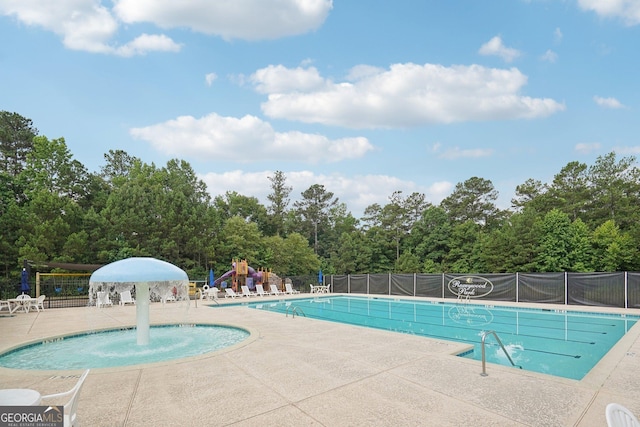 view of swimming pool with a patio, pool water feature, and a playground