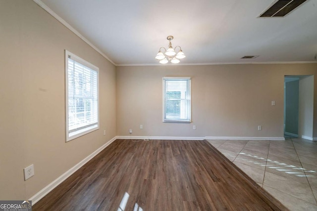 unfurnished room with an inviting chandelier, ornamental molding, and hardwood / wood-style floors