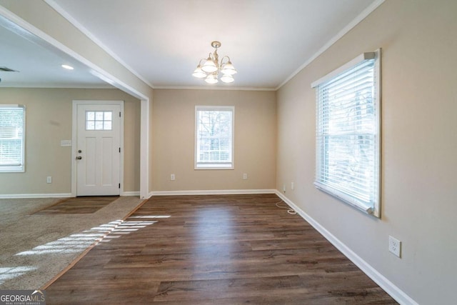 entryway featuring an inviting chandelier, crown molding, a wealth of natural light, and dark wood-type flooring