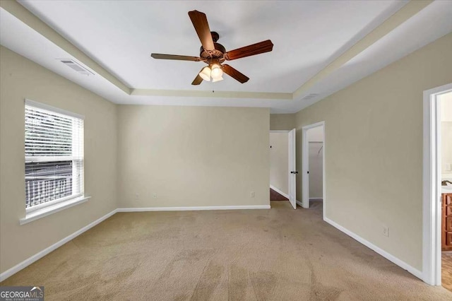 unfurnished room featuring light carpet, a raised ceiling, and ceiling fan