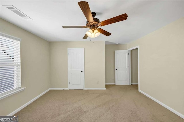 unfurnished bedroom with multiple windows, light colored carpet, and ceiling fan