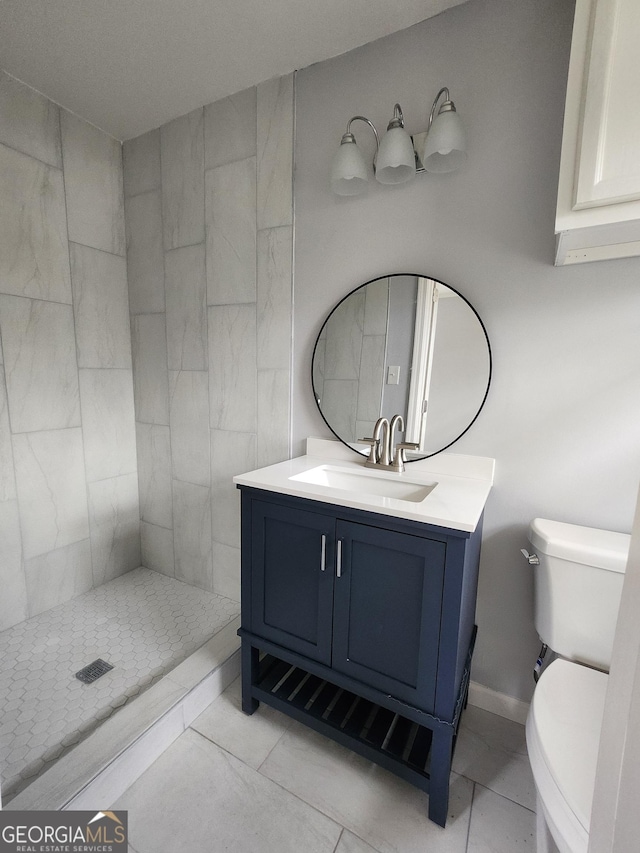 bathroom with tiled shower, vanity, and toilet